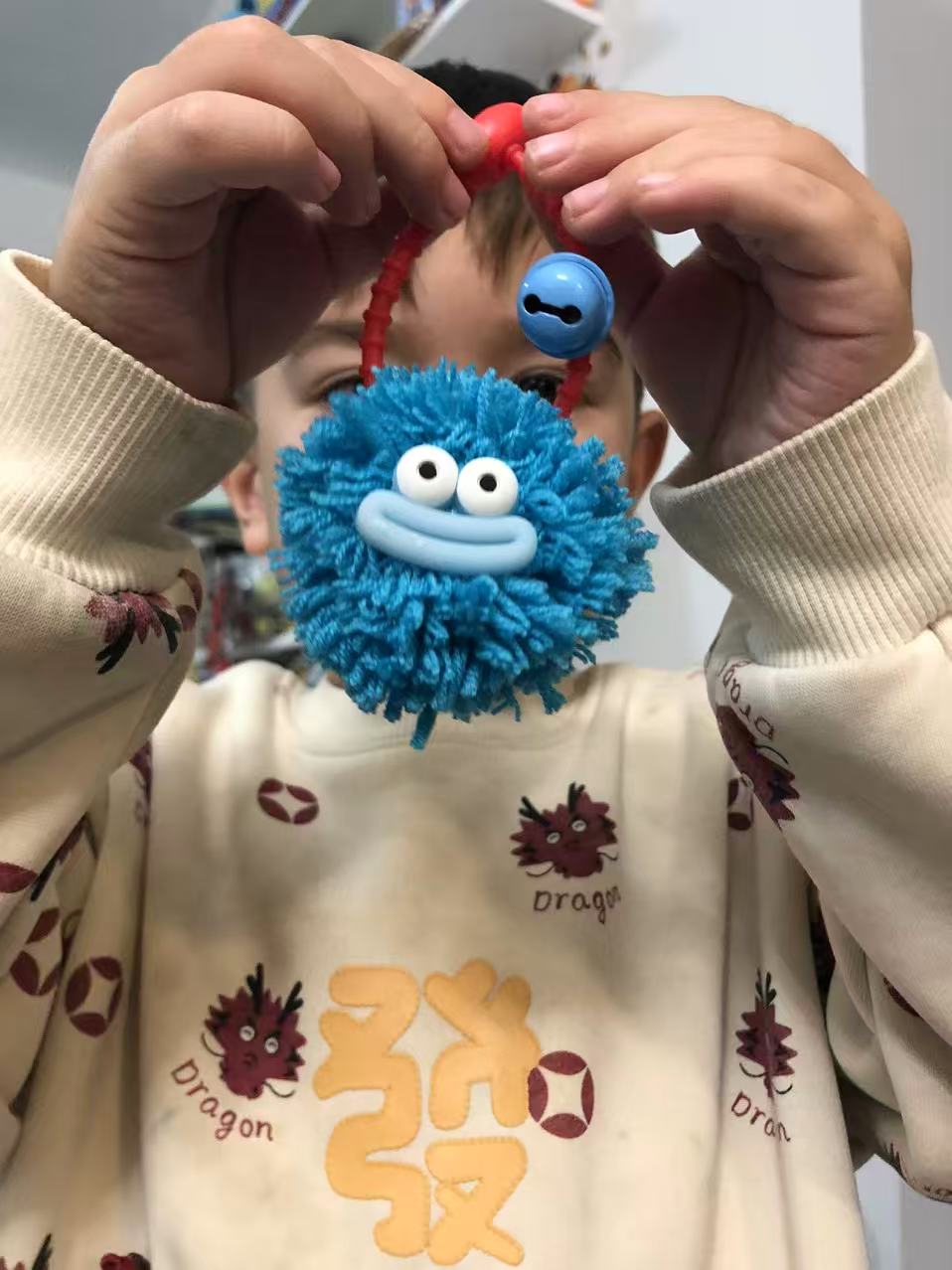 Child holding pompom phone accessory